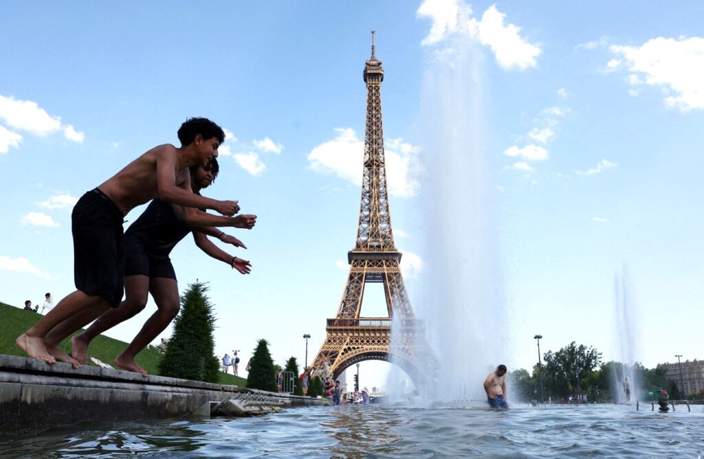 Sejumlah warga Prancis menyejukkan diri di kubangan Air Mancur Trocadero di dekat Menara Eiffel, Paris. (Foto: Abdul Saboor/Reuters)