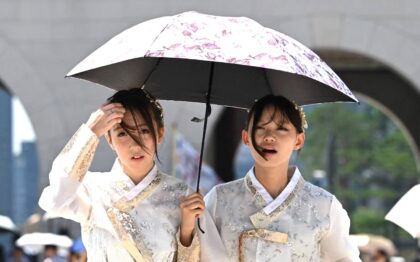 Dua gadis melindungi dirinya dari sengatan matahari dengan menggunakan payung di Istana Gyeongbokgung, Seoul. (Foto: AFP-JIJI)